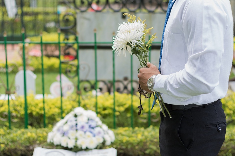 Simple funeral- man holding flowers at a funeral